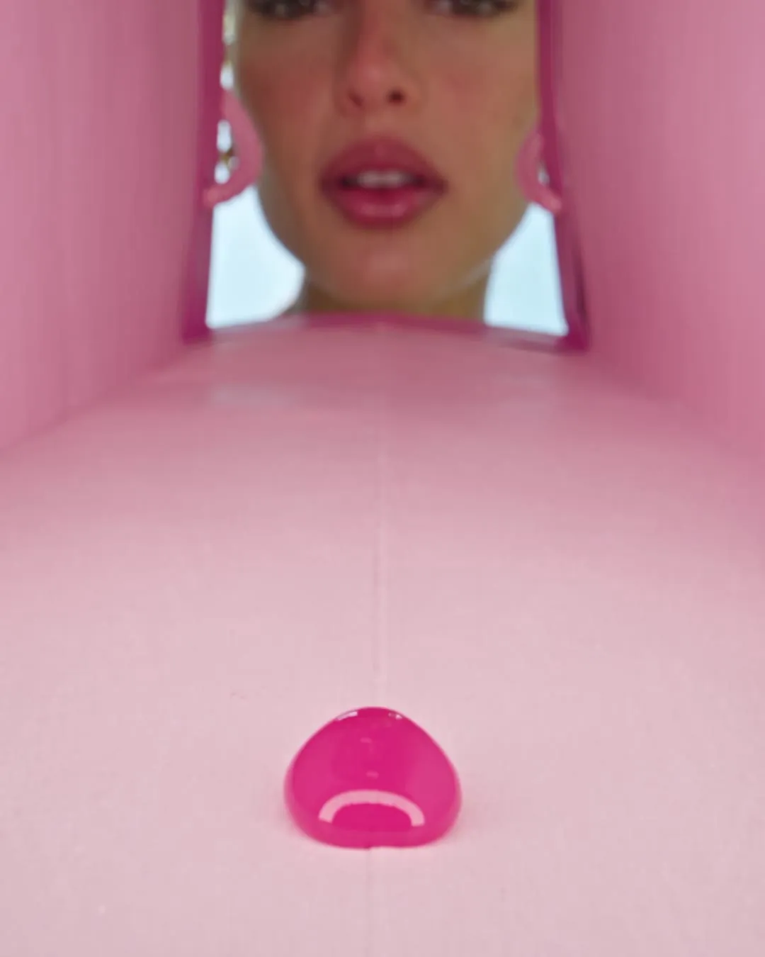 A single bead of pink gel falling toward the lens inside the bag.