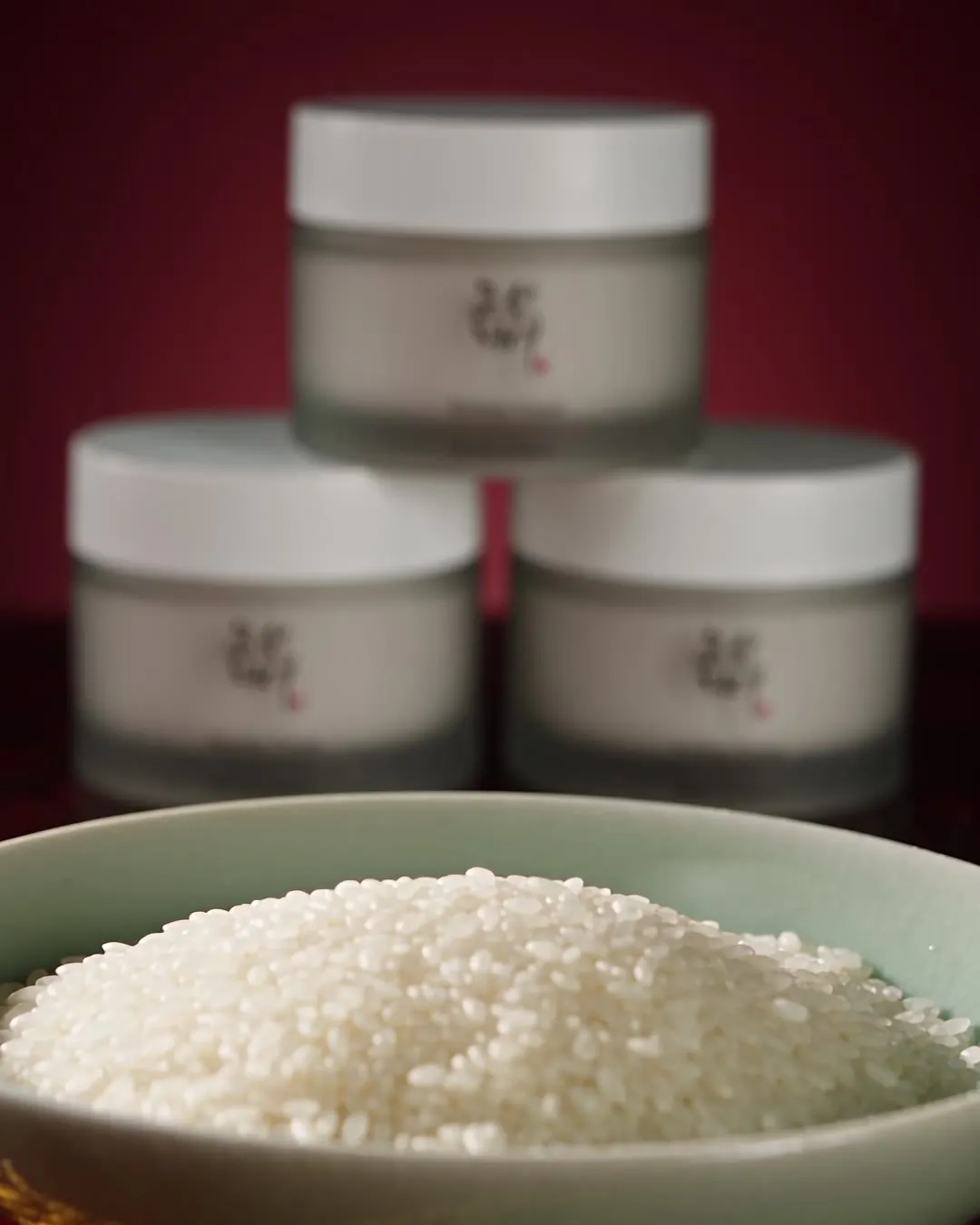 Rice in a celadon bowl beside heritage skincare jars.